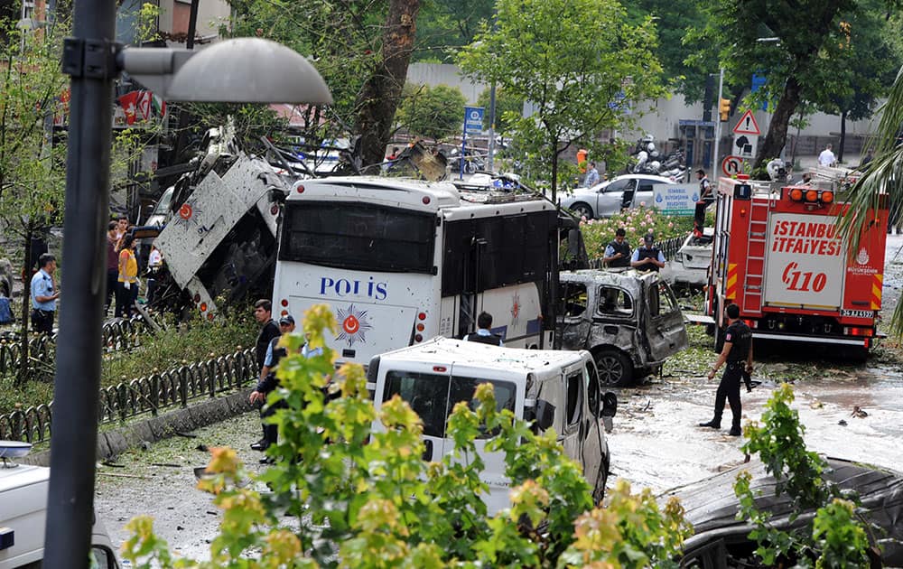 Turkish security officials and firefighters work at the explosion site after a bus carrying riot police official was struck by a bomb in Istanbul