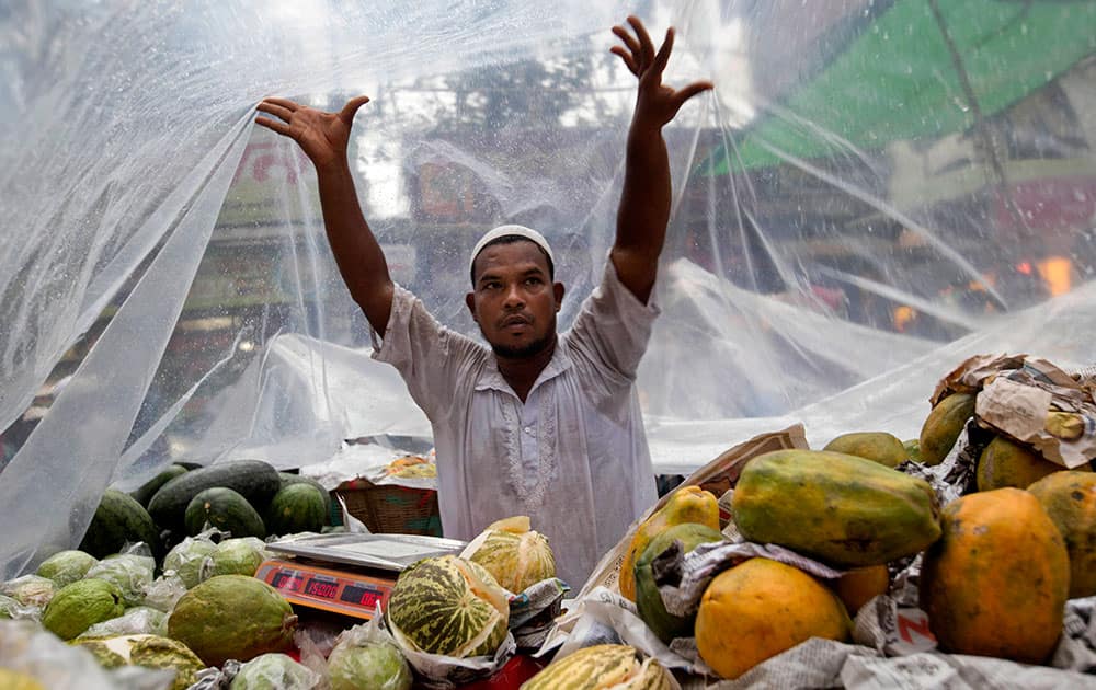 A Bangladeshi roadside fruits vendor covers his shop by a plastic sheet as muslims devotees buy food from a market to break the first day of the holy fasting month of Ramadan in Dhaka, Bangladesh