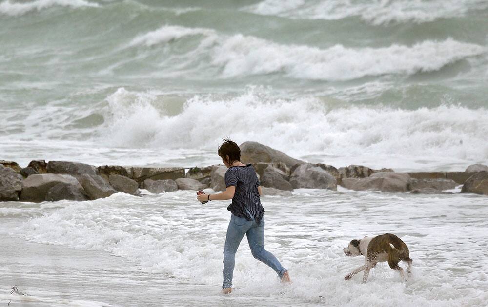 A woman runs in the heavy surf with her dog at Sunset Beach in Treasure island.