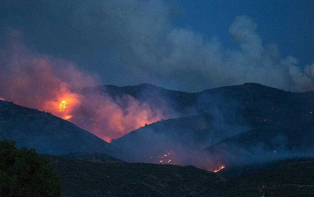 Flames from the Tenderfoot Fire dot the side of a hill overlooking Peeples Valley, Ariz.