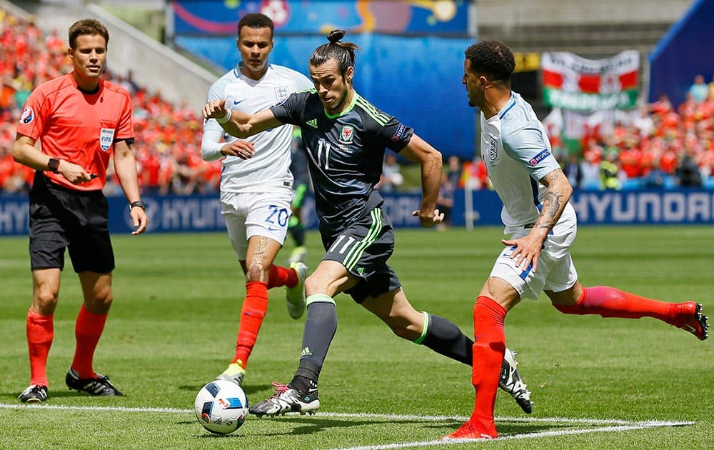 Wales' Gareth Bale, center, drives the ball through England's defense during the Euro 2016