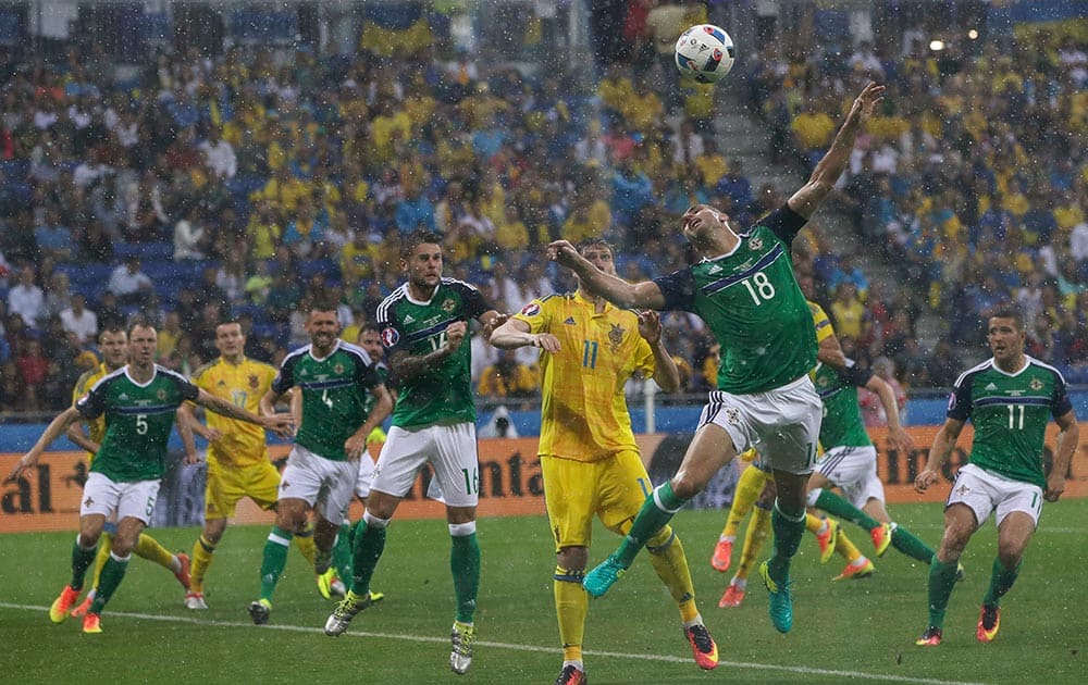 Northern Ireland's Aaron Hughes, center right, jumps for the ball during the Euro 2016