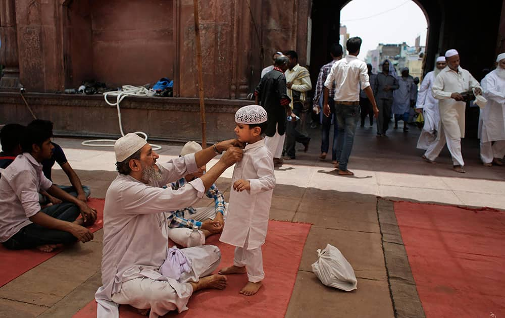 A Muslim man grooms a young boy as they wait to offer prayers