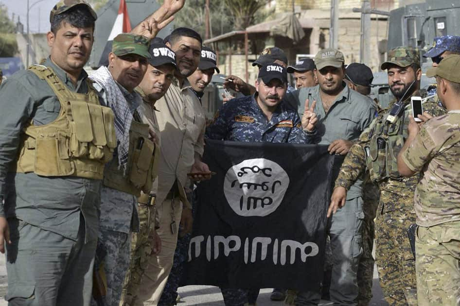 Iraqi security forces celebrate as they pose with a flag of the Islamic State group