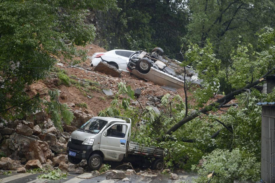 damaged vehicles are stuck on a section of road blocked by a landslide