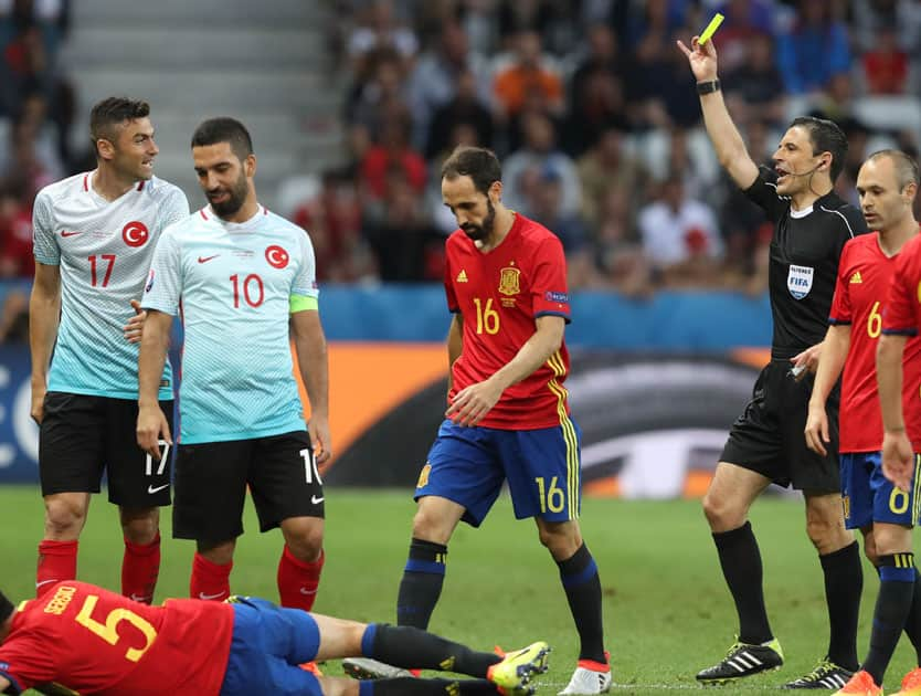 Referee Milorad Mazic shows a yellow card to Turkey's Burak Yilmaz