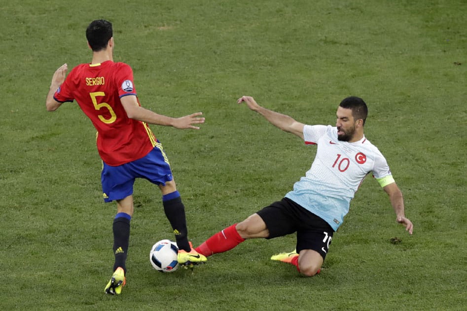 Cesc Fabregas is tackled by Turkey's Arda Turan