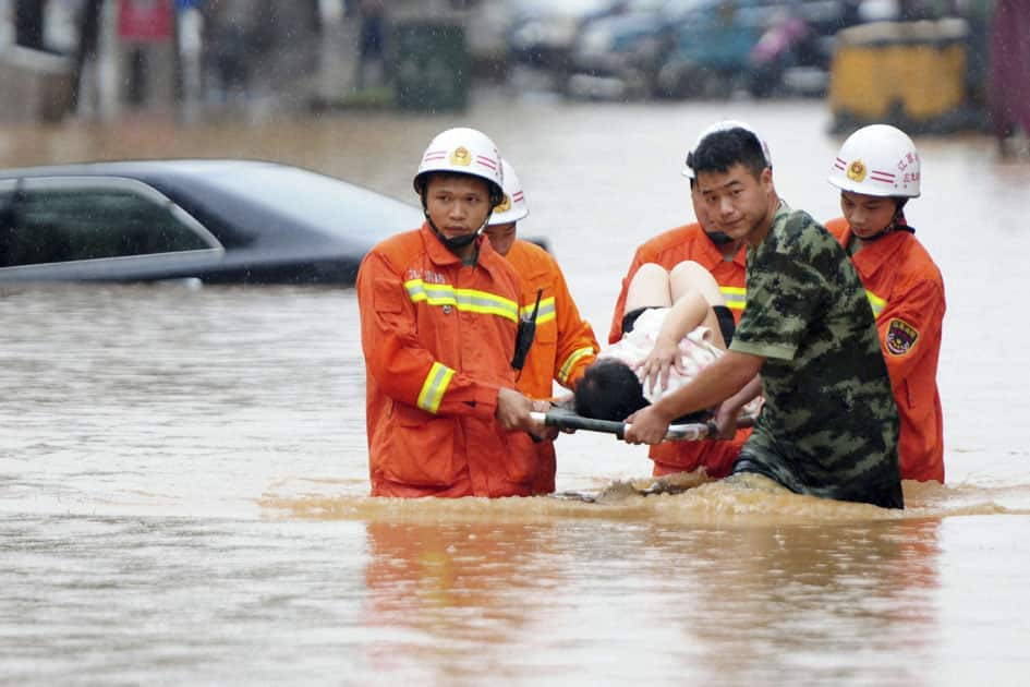 Rescuers carry a woman on a stretcher through a flooded area