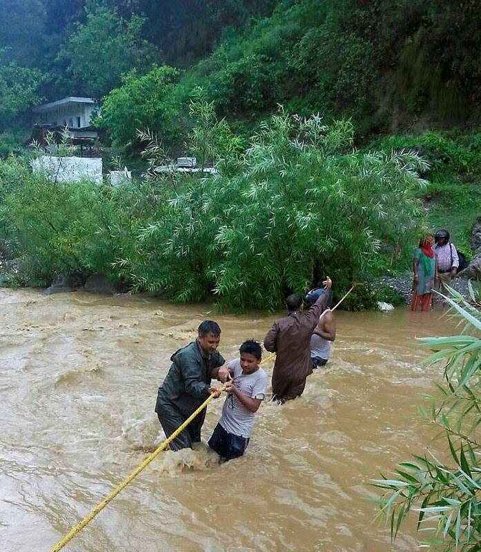 Policemen help stranded people cross river