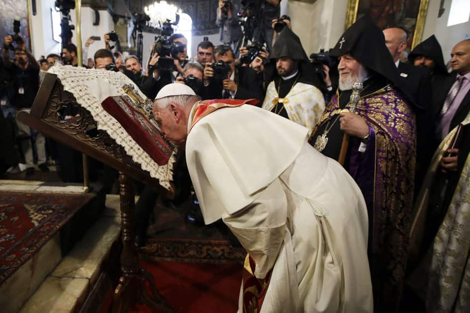 Pope Francis flanked by Catholicos Karekin II, right, kisses a Holy Book