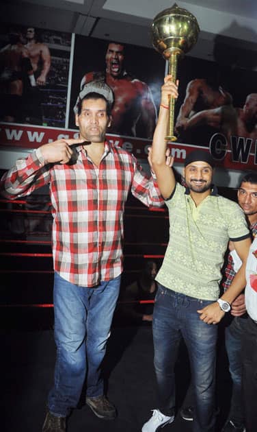 Cricketer Harbhajan Singh holds a mace with WWE wrestler Great Khali