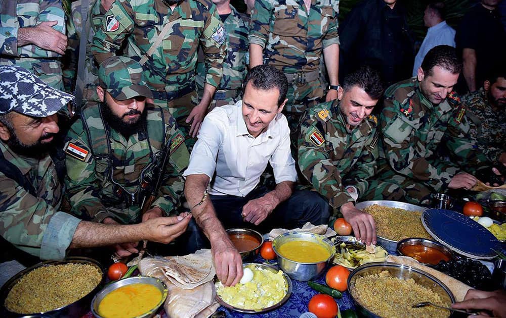 Syrian President Bashar Assad sits with Syrian troops