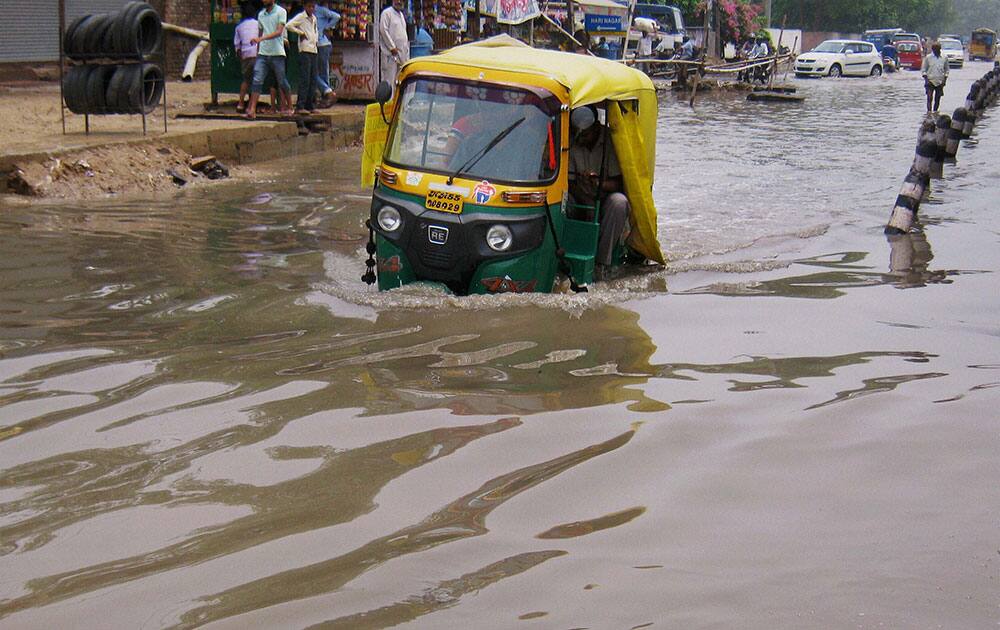 An autorickshaw moves through a water logged road after heavy rains in Gurgaon