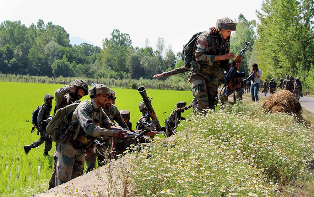 Army persons move towards the house where a Hizbul Mujahideen militant was hiding