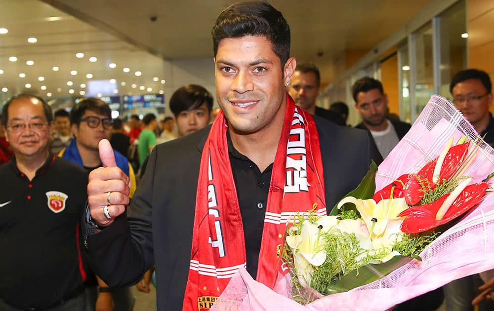 Brazilian soccer player Hulk gives a thumbs-up as he arrives to fans waiting at the airport in Shanghai