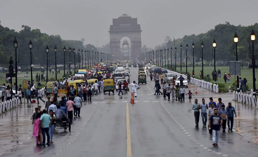 Visitors enjoy the rain at Rajpath in New Delhi.