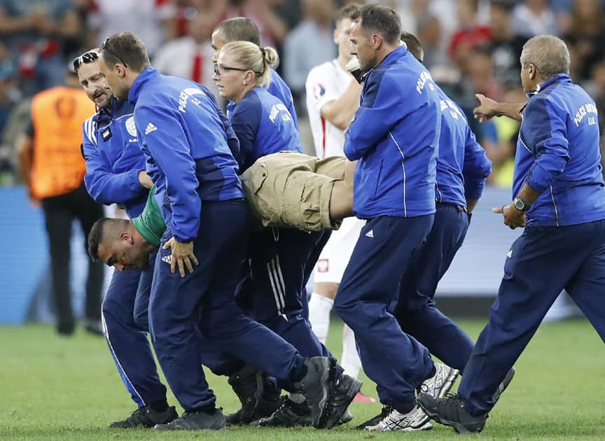 Stewards carry away a fan who ran into the pitch