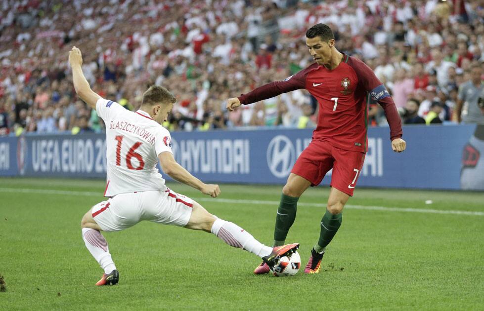 Cristiano Ronaldo, right, is tackled by Poland's Jakub Blaszczykowski