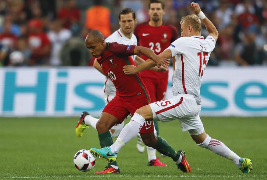 Poland's Kamil Glik, right, challenges Portugal's Joao Mario