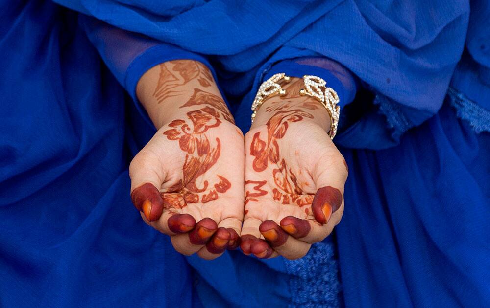 A Muslim girl, hands decorated with henna offers Eid al-Fitr prayers in an open groun A Muslim girl, hands decorated with henna offers Eid al-Fitr prayers in an open groun