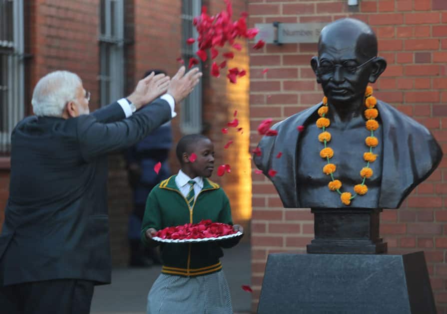 Narendra Modi throws petals over a bust of Mahatma Gandhi