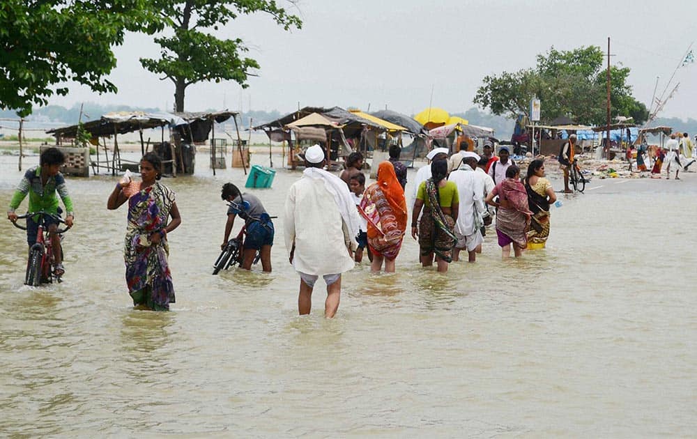 Locals walk at a road flooded after heavy rains in Allahabad.