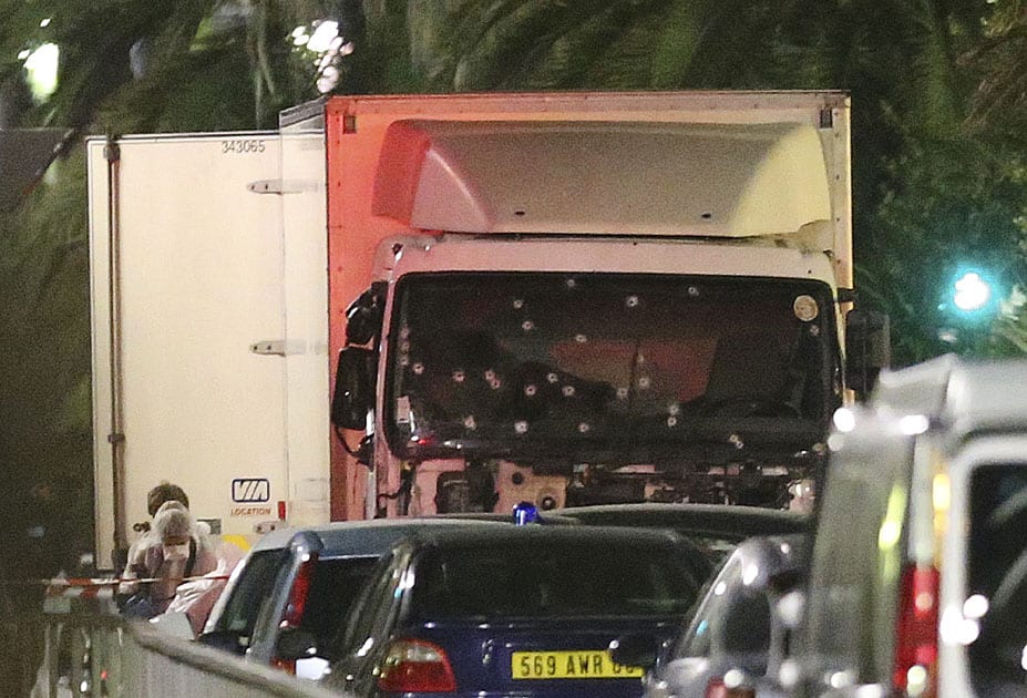 A policeman stands, watching the truck used for the attack