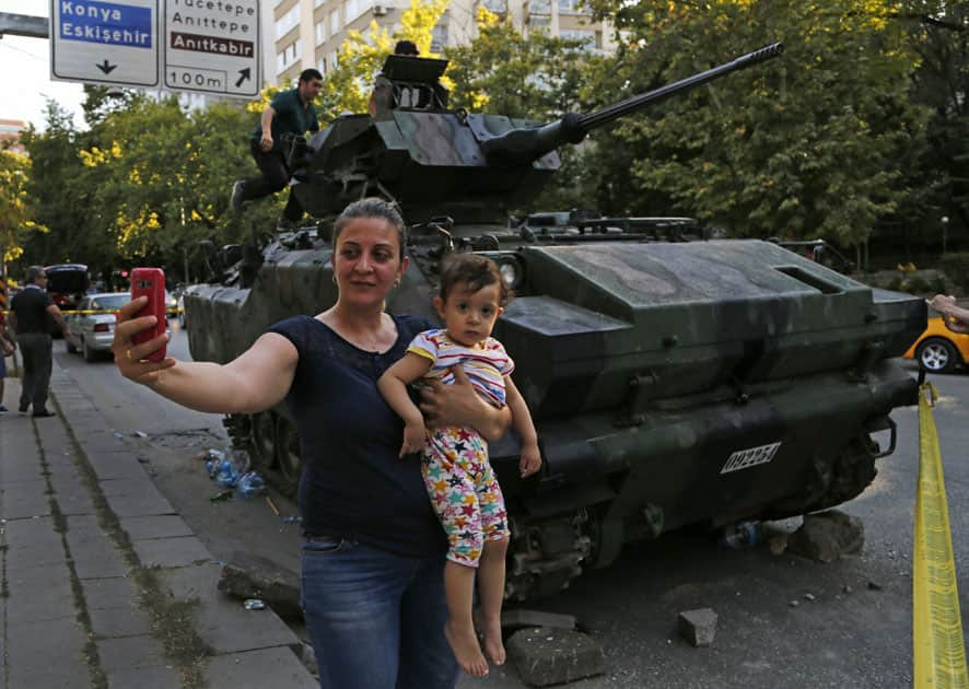 woman holds her baby as she takes a selfie