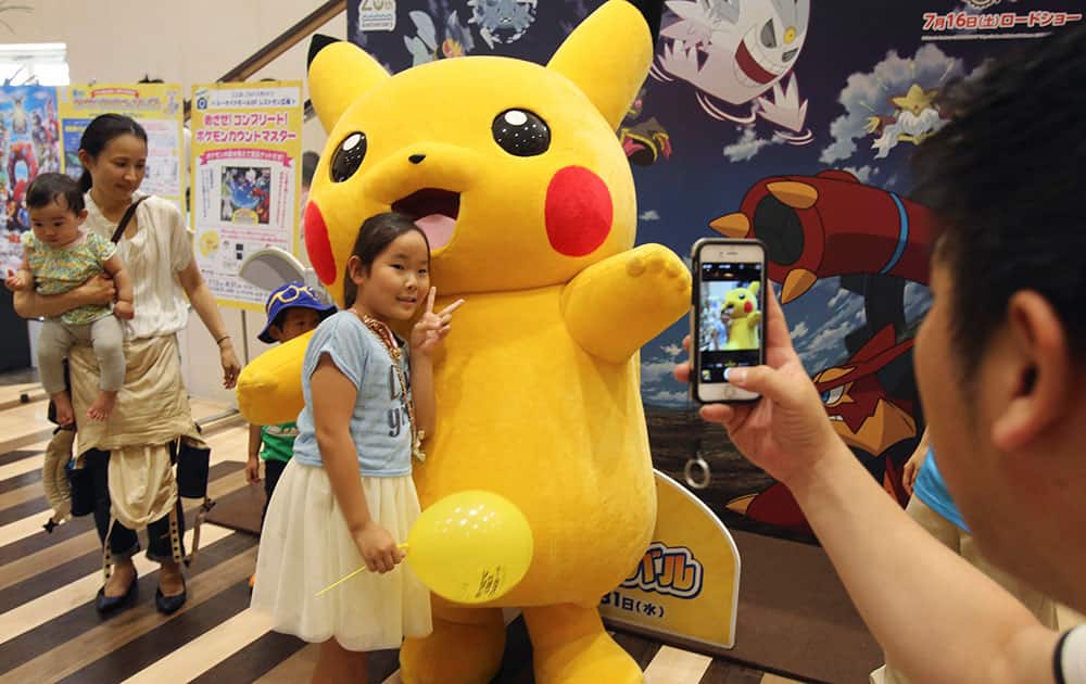 A girl poses with Pikachu for photos during a Pokemon festival in Tokyo