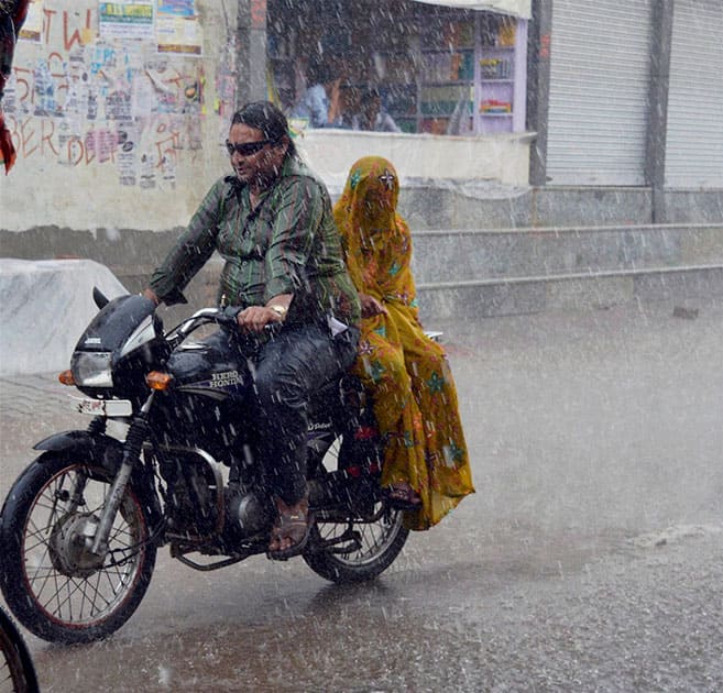 A couple rides a motorcycle in heavy rains in Mathura