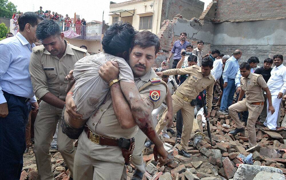 olice men carrying an injured to hospital after an underconstruction building collapsed