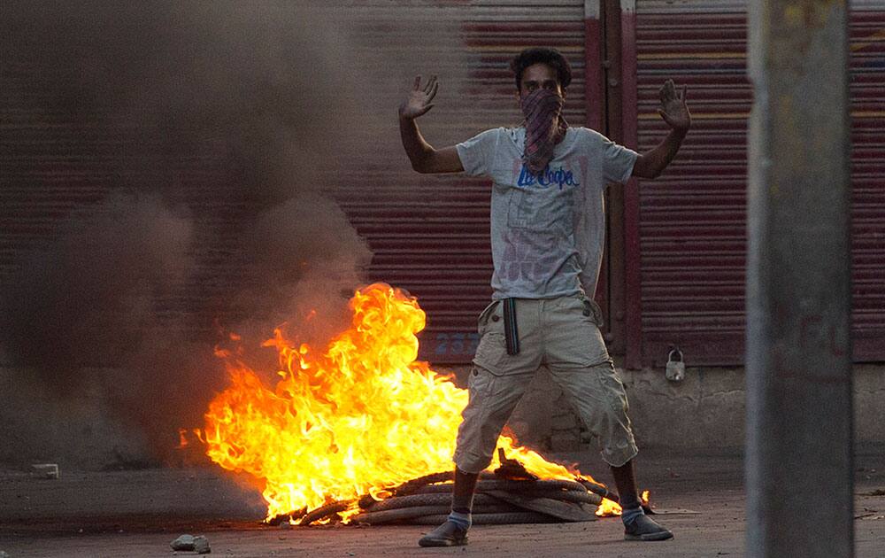 A masked Kashmiri protester shouts slogan