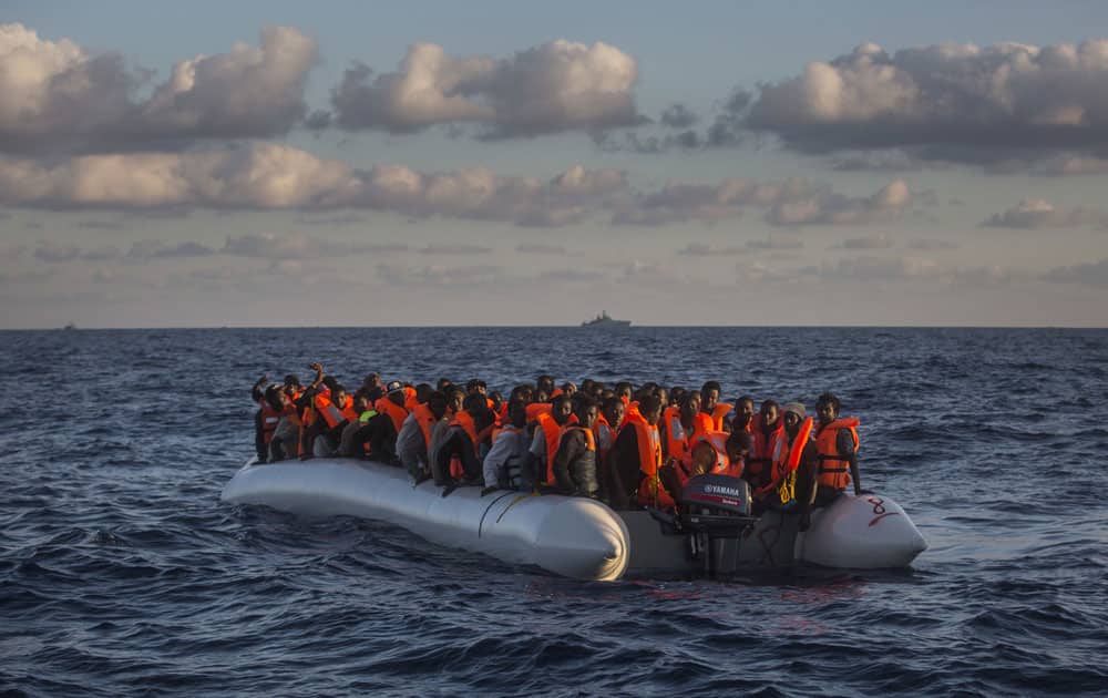 Sub-saharan refugees and migrants on an overcrowded dinghy wait to be rescued by a team
