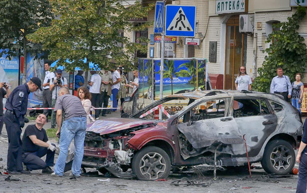 Forensic experts examine the wreckage of a burned car in Kiev, Ukraine.