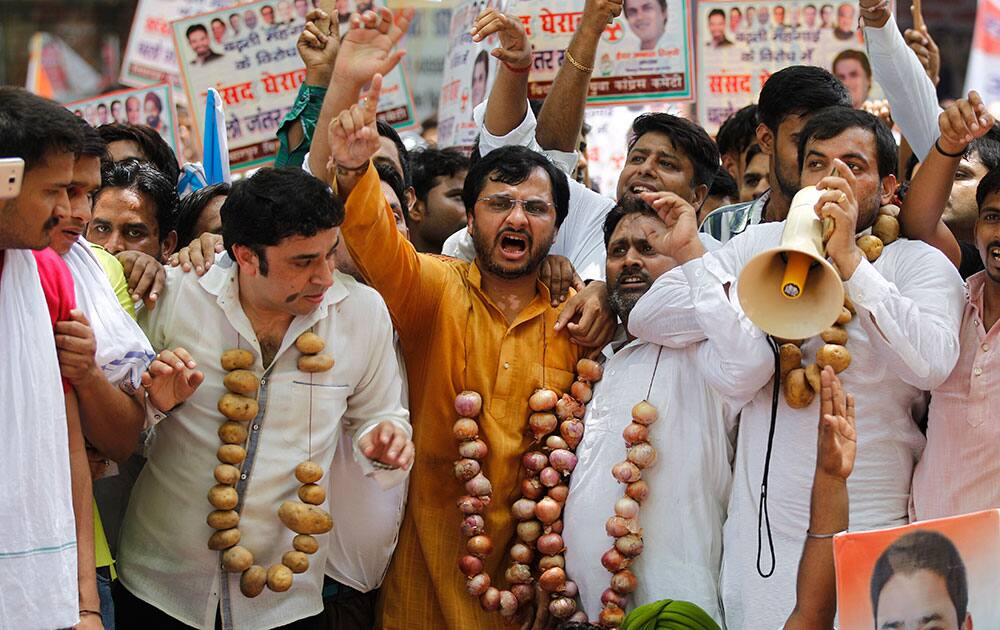 Congress party activists, wearing garlands made of vegetables, shout slogans during a protest against rising prices