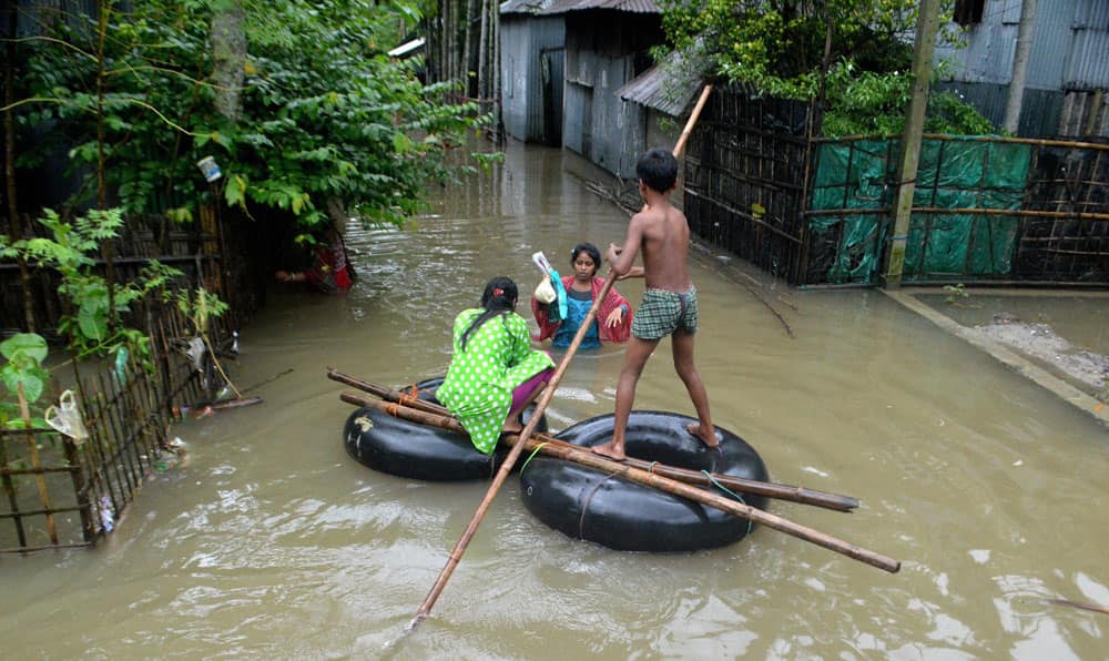 A girl and boy on a Wheel Tube wade through a flooded area