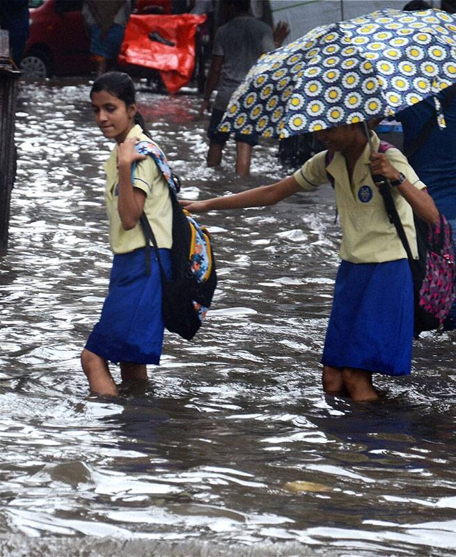 People cross water-logged roads during heavy rains in Kolkata People cross water-logged roads during heavy rains in Kolkata