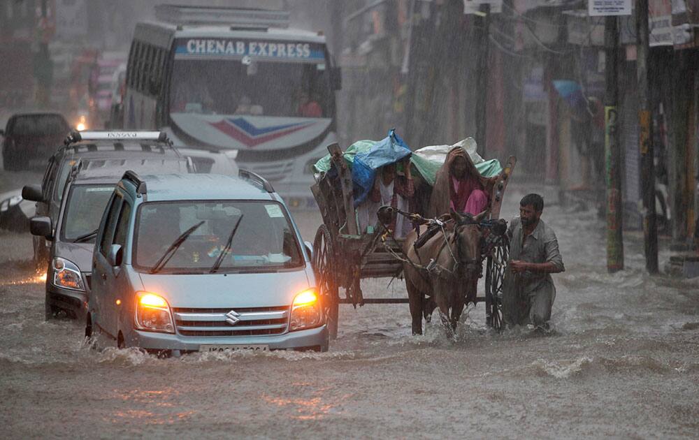 An Indian man pushes a horse cart carrying passengers in the rain in Jammu. An Indian man pushes a horse cart carrying passengers in the rain in Jammu.