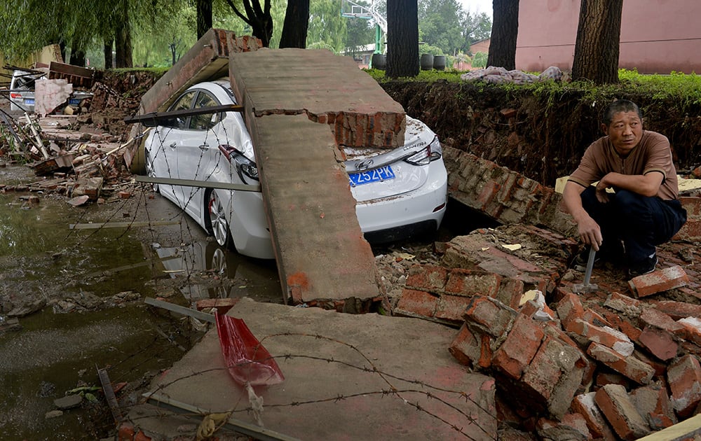 A man takes a rest near damaged vehicles following a flood in Shenyang in northeast China's Liaoning province A man takes a rest near damaged vehicles following a flood in Shenyang in northeast China's Liaoning province