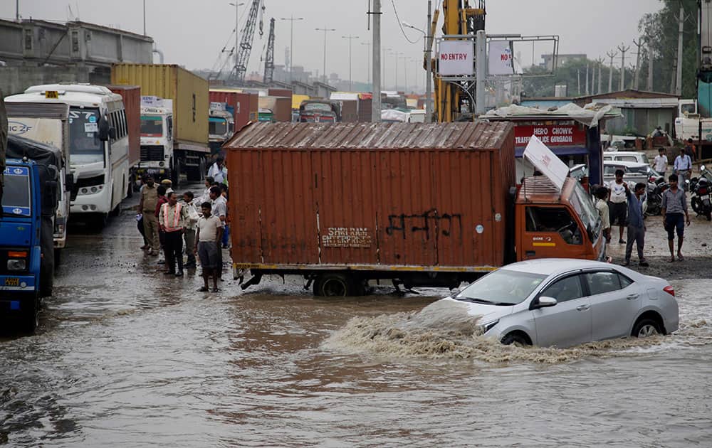 A car navigates its way through a flooded street after heavy rainfall in Gurgaon A car navigates its way through a flooded street after heavy rainfall in Gurgaon