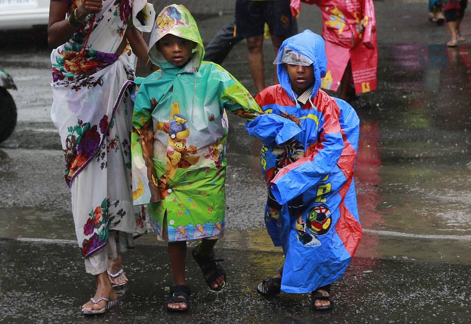 Children return from school wearing colorful raincoats in the rain in Mumbai.