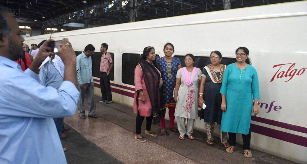 Women posing for photo in front of Spanish train Talgo