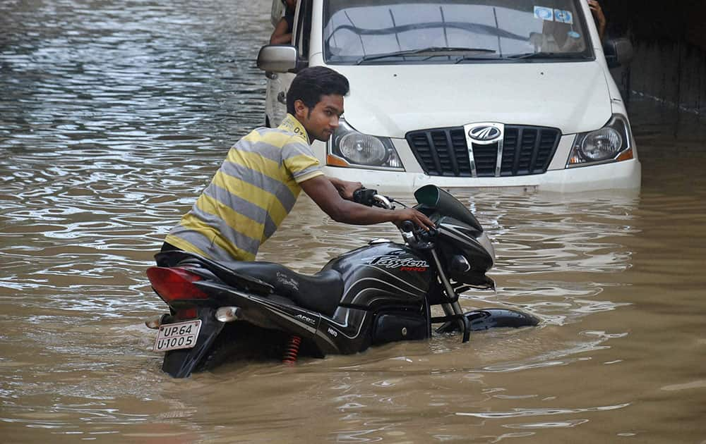 A boy pushing his bike through a flooded road after heavy rains in Mirzapur