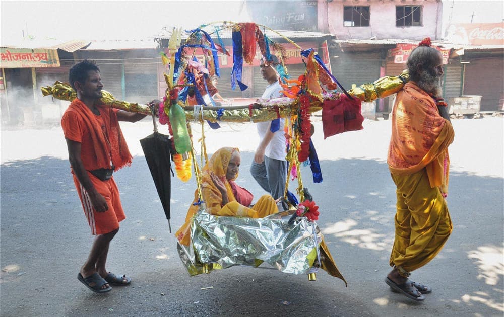 Devotees carrying a woman in a Kanwar in Meerut.