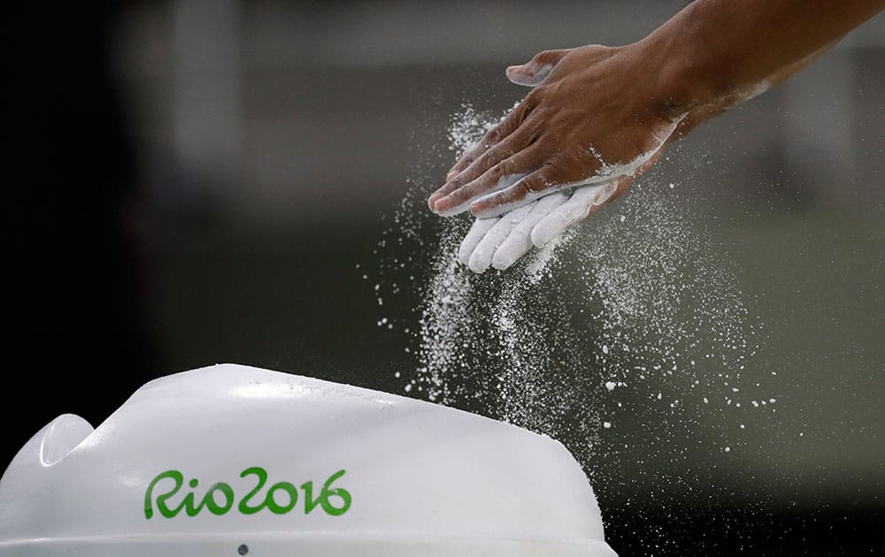 Gymnast Marios Georgiou from Cyprus rubs chalk on his hand before performing on an apparatus ahead of the 2016 Summer Olympics in Rio de Janeiro, Brazil