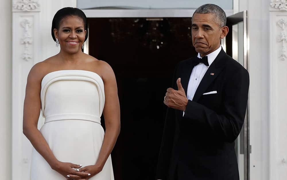 President Barack Obama flashes a thumbs up after gesturing toward first lady Michelle Obama, as they wait for Singapore's Prime Minister Lee Hsien Loong