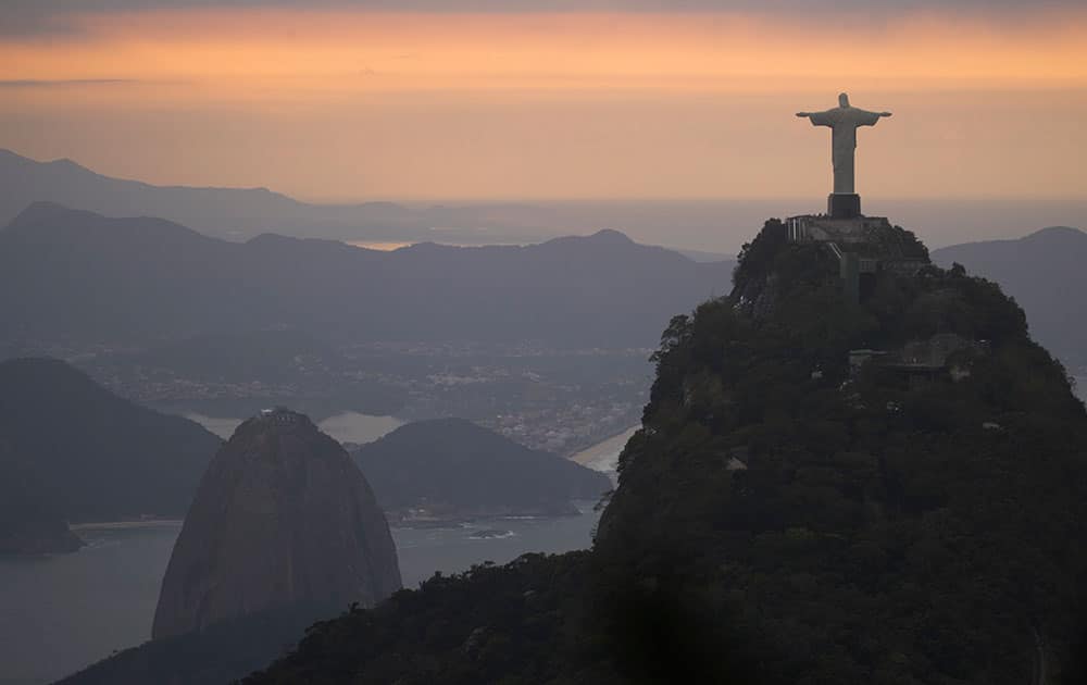 The Christ the Redeemer statue and Sugar Loaf mountain stand as the sun rises in Rio de Janeiro, Brazil