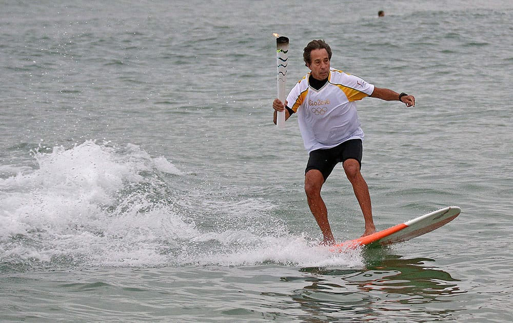 Brazilian Rico de Souza surfs with the Olympic torch