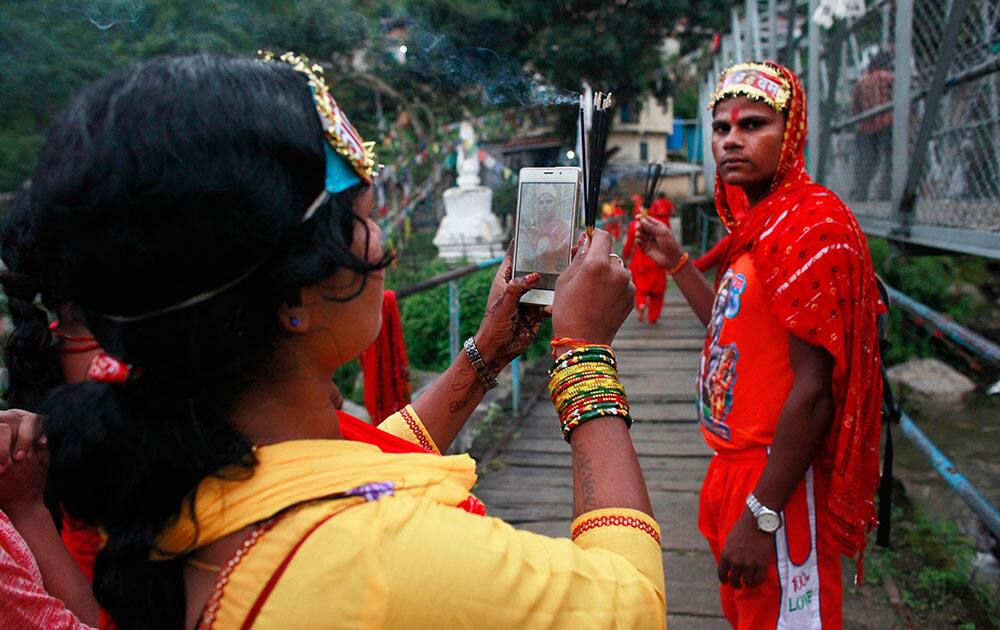 A Hindu devotee takes photos of her friend during Bol Bom pilgrimage, on the outskirts of Kathmandu, Nepal A Hindu devotee takes photos of her friend during Bol Bom pilgrimage, on the outskirts of Kathmandu, Nepal
