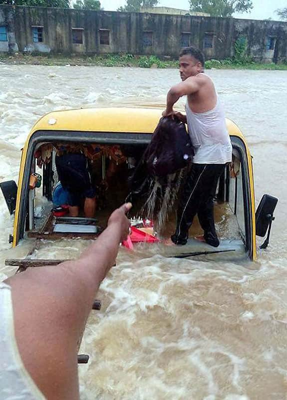 A man taking out school bags from the bus which fell into a river children were rescued by locals during rains, at Bijolia